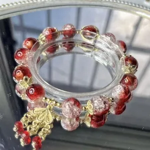 Close-up of red and white crackle glass beaded bracelet with gold flower charms.