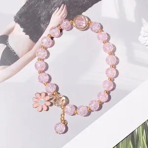 Macro detail of a pink beaded bracelet with floral charm and gold-toned spacers