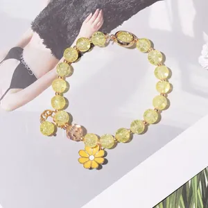 Detailed macro shot of yellow crackle bead bracelet featuring a vibrant sunflower charm
