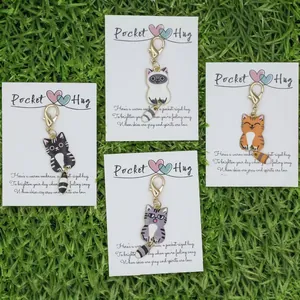 Close-up of four cute cartoon cat keychains with Pocket Hug cards on grass