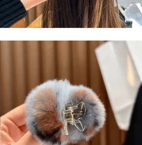 Detailed view of a plush hair claw clip featuring soft grey and brown faux fur pom-poms