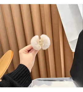 Close-up of white plush fur ball hair claw clip held in hand for hair styling