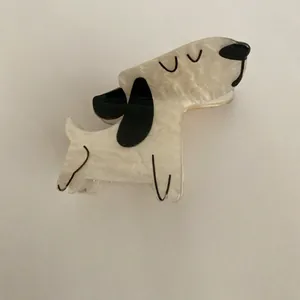 Close-up of a cute cream-white dog-shaped acetate hair claw clip with black details.