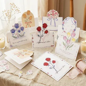 A variety of floral greeting cards with rose and tulip designs on a warm rustic table