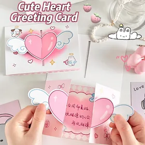 Close-up of 3D folding greeting card with pink winged heart and cute rabbit illustration.