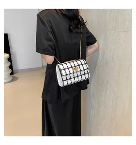 Close-up detail of a white and black checkered tweed chain bag worn by a model in a black dress