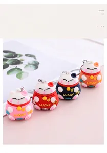 Detailed view of four colorful 3D lucky cat cartoon keychains on pink background
