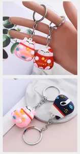Detailed close-up showing variety of colorful cartoon lucky cat keychains with silver rings