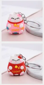 Macro view of pink and red Maneki-neko keychains with embossed Lucky text detail