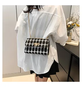 Woman wearing a black and white plaid tweed chain crossbody bag over a white shirt