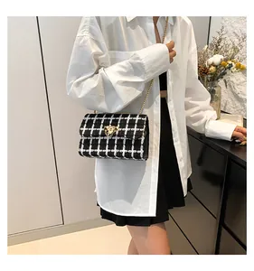 Close-up of a stylish checkered crossbody bag with gold chain worn by a model