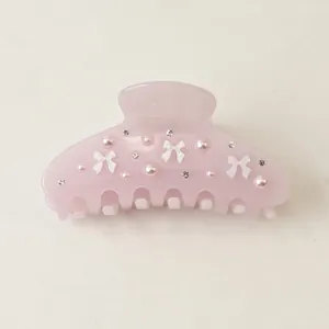 Detailed macro view of pink acetate hair claw clip featuring 3D white bows and pearls