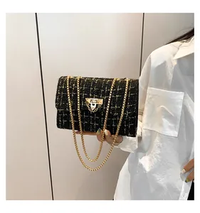 Elegant black and gold tweed plaid crossbody bag with gold chain strap held by model