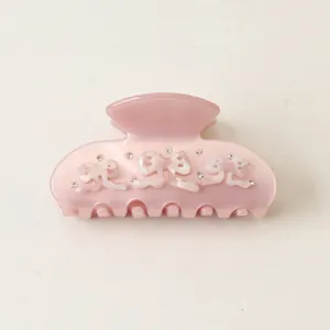 Detailed view of a pink acetate hair claw clip with 3D bows and rhinestones