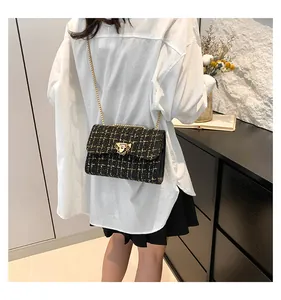 Elegant black and yellow tweed chain shoulder bag worn by model in a stylish indoor setting