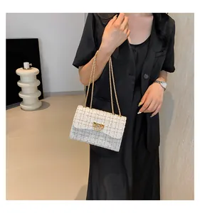 Elegant white tweed shoulder bag with gold chain strap worn by model in minimalist setting