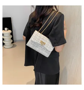 Rear view of a model wearing a white tweed plaid shoulder bag with a gold chain.