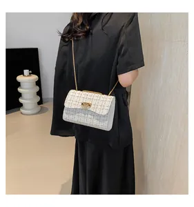 Model carrying a white tweed plaid chain strap crossbody bag against black clothing