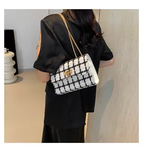 Checkered tweed shoulder bag with gold chain strap worn by model in black blazer