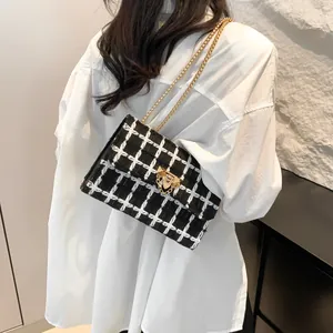Elegant black and white checkered tweed shoulder bag with luxury gold chain strap and lock
