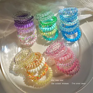 Set aus leuchtenden Spiral-Haargummis auf einem weißen Keramikteller.
