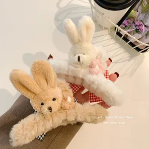 Close-up detail of plush rabbit hair claw clip with soft faux fur and red plaid ribbon