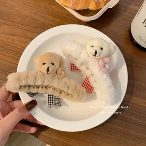 Close-up of fluffy plush bear hair claw clips in brown and cream colors on a white plate