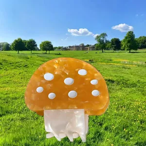 Dettaglio di una molletta per capelli a fungo in acetato arancione in un prato verde
