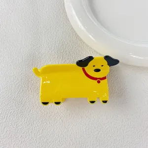 Detail view of a cute yellow cartoon dog acetate hair claw clip on white background