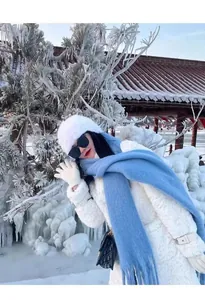 Elegant light blue cashmere-feel winter scarf worn by a model in a snowy landscape