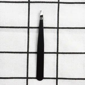 Detail view of professional matte black slant tip eyebrow tweezers on checkered background