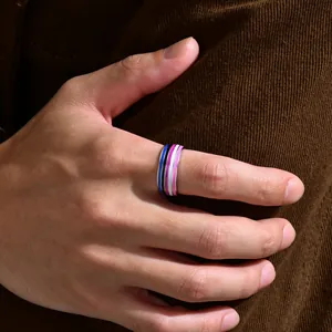 High-quality detail shot of an 8mm genderfluid pride flag striped ring on a hand