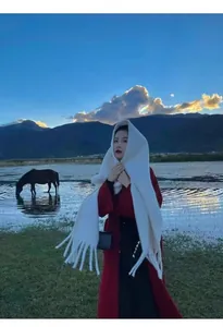 Elegant white solid color thick scarf with tassels worn by a model in outdoor lake scene