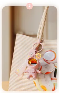 Pink astronaut keychain bag charm with SPACE strap attached to a stylish checked bag