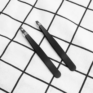 Professional black slanted eyebrow tweezers shown in detail on a grid background cloth