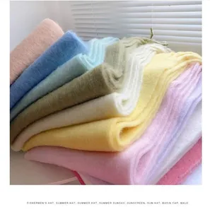 Detailed close-up of the soft plush texture and colors of stacked winter scarves