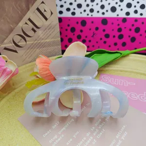 Close-up of a marbled acetate pumpkin hair claw clip with gold lettering detail