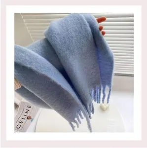 Close-up of a thick light blue plush scarf with soft fringe details and fluffy texture