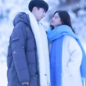Romantic couple wearing thick solid color warm scarves in a beautiful snowy winter setting.