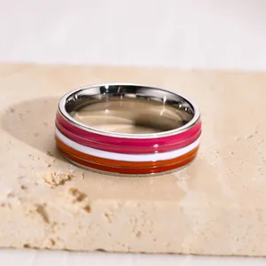 Macro view of 8mm stainless steel ring with vibrant lesbian pride flag enamel stripes