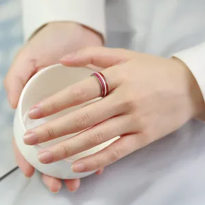Detailed view of a vibrant 8mm rainbow striped ring worn on hand holding a white cup