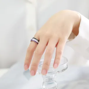 Macro detail view of an 8mm asexual pride flag ring worn on a hand with white background
