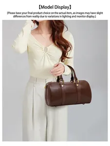 Model holding a vintage brown Boston bag with elegant top handles and golden hardware.