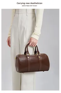 Retro brown faux leather Boston pillow handbag held by model in minimalist style