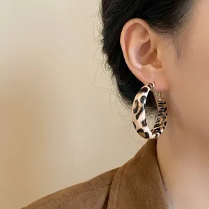Close-up detail of retro leopard print leather hoop earrings with a gold-tone finish.