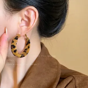 Detailed close-up showing stylish leopard print leather hoop earring on model's ear