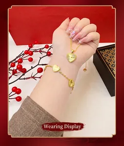 Close-up of elegant heart-shaped sand gold necklace and bracelet set on wrist