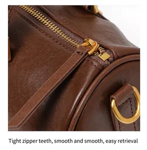 Macro detail of the high-quality gold zipper and textured leather on a brown Boston bag