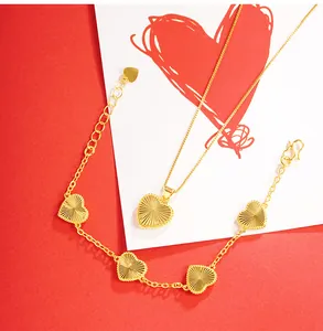 Detail shot of gold heart necklace and bracelet set with radiant sunburst texture finish.