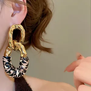 Close-up of vintage geometric earrings with gold finish and leopard print leather details